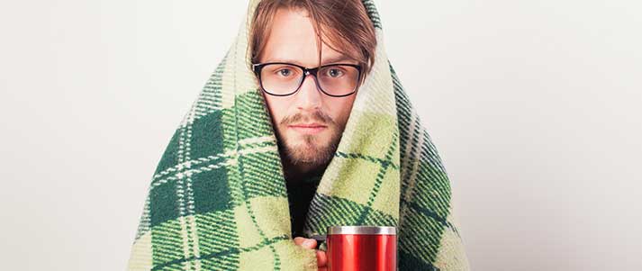 Man wrapped in green blanket with mug
